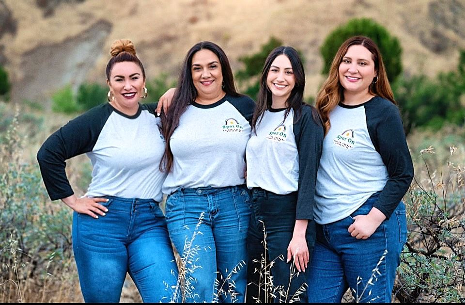 Four women in white shirts and blue jeans.