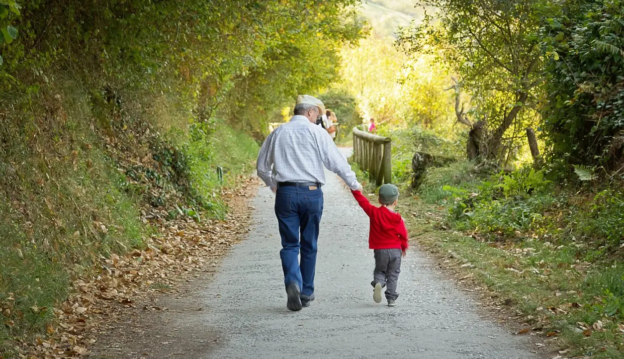 A man and boy walking down the road holding hands.