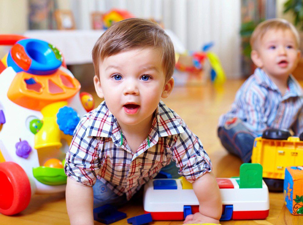 A young boy is playing with toys on the floor.